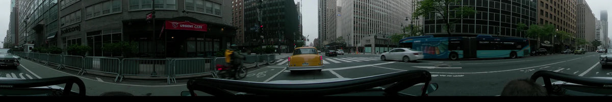 Towering skyscrapers flank Second Avenue and East 42nd Street in New York, where a yellow vintage car drives on an overcast spring morning.