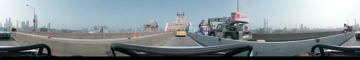 A yellow vintage car leads the way toward the Queensboro Bridge in New York, United States, under a clear spring sky during the day.