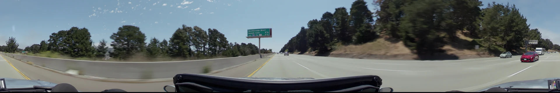 A multi-lane highway in San Francisco with a green overhead sign for Westborough Blvd and Sneath Lane, flanked by dense green trees and light traffic.