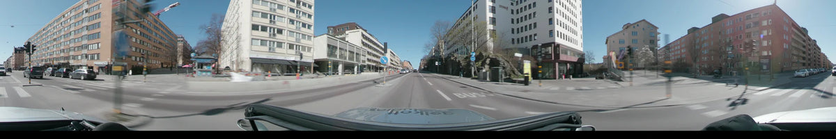 White buildings and a rocky hillside line this city street in Stockholm, Sweden, during a clear spring day, viewed from a car.