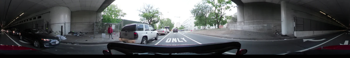 Passing white buildings and green trees, a car navigates a marked lane through Washington, United States, during a partly cloudy spring afternoon.