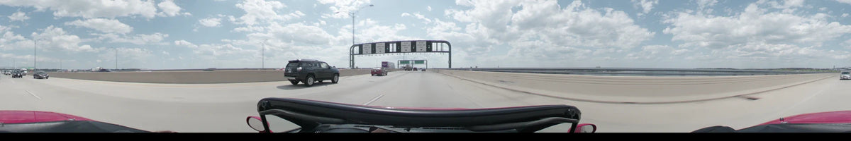 Overhead stop signs and other traffic are visible as a car travels a multi-lane highway in Washington on a partly cloudy spring afternoon.