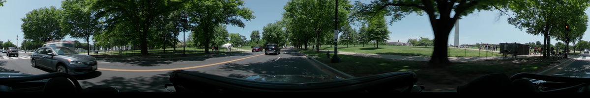 A daytime car driving shot through Washington, United States, on a clear spring day, featuring a road lined with lush green trees and other vehicles.