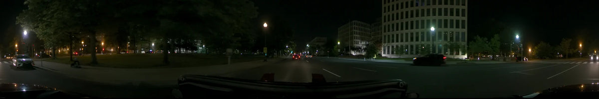 Driving through a clear spring night in Washington, United States. The view from the car shows illuminated city streets, distant traffic, and large urban buildings.
