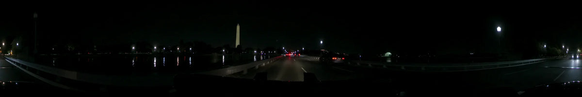 The illuminated Washington Monument stands out against the dark sky in Washington, United States, as a car moves through traffic on a clear spring night.