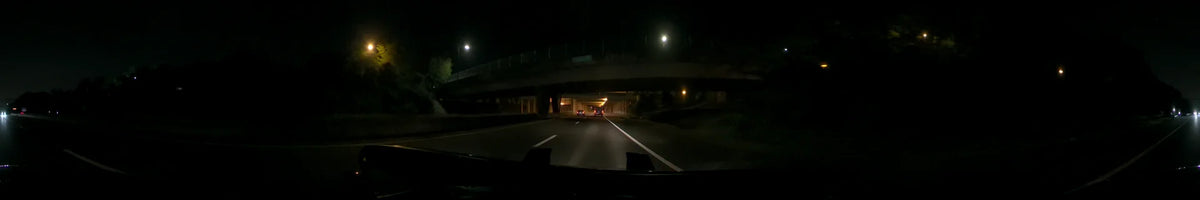 Two vehicles lead the way as a car passes beneath a dark overpass and streetlamps in Washington, United States, on a clear spring night.