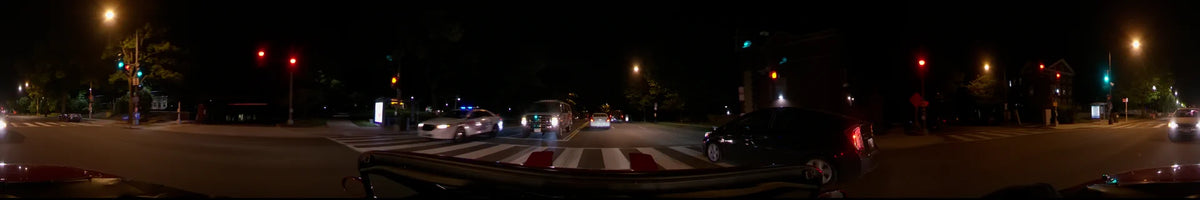 Police vehicles with flashing emergency lights occupy a street crossing in Washington, United States, during a clear spring night, viewed from inside a car.