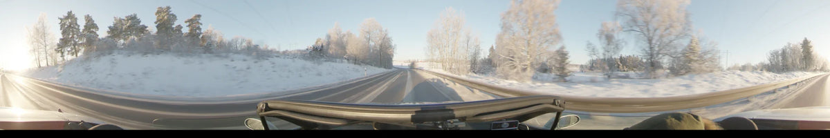 Frost-covered trees line a snowy road in Uppsala, Sweden. This daytime car footage captures a clear winter landscape under a bright sky.