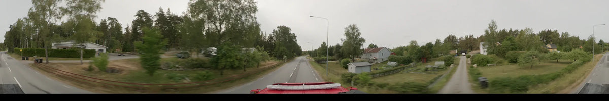 View from a bus driving through a residential area in Märsta, Sweden, on an overcast summer morning, featuring a two-lane road lined with green trees.