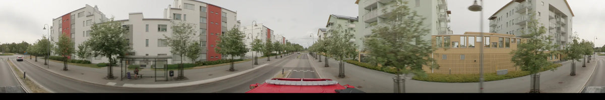 Contemporary apartment buildings and young trees flank the road in Märsta, Sweden, during an overcast summer morning as seen from a bus.