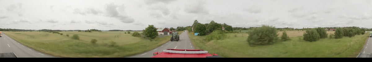 On an overcast summer morning in Märsta, Sweden, a red bus encounters an oncoming green tractor and red houses along the road.