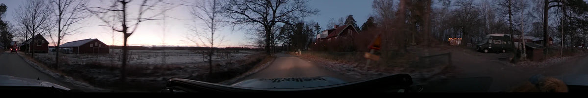 On a clear autumn afternoon in Lennartsnäs, Sweden, a car travels past a traditional red house and bare trees bordering a rural road.