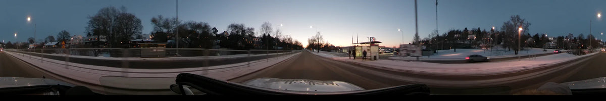 Under a clear winter sunset, a car travels past a Coop store and pedestrians waiting at a bus stop in Stockholm, Sweden.