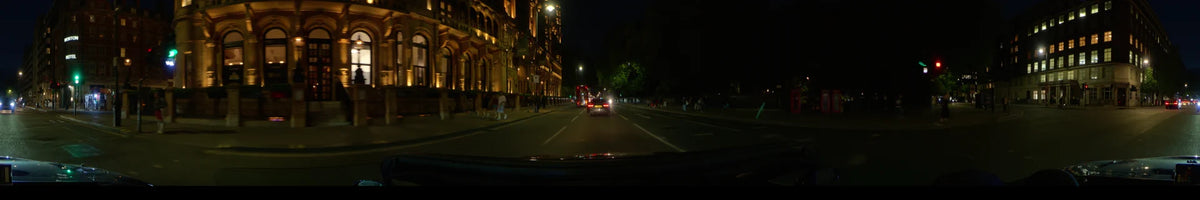 Nighttime car drive through London, United Kingdom, passing The Savoy hotel with a red double-decker bus ahead on the road during spring.