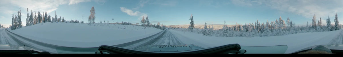 In Dalarna, Sweden, a car travels along a snowy winter road past snow-covered trees and