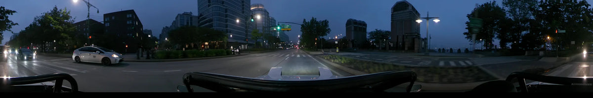 Under an overcast dawn sky in spring, a car passes a Holland Tunnel sign and modern buildings on a New York street in the United States.