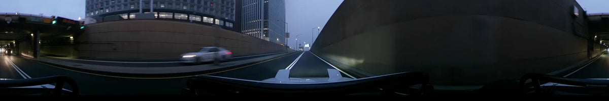 Modern skyscrapers and concrete barriers line a New York road as a car drives through the fog during a spring dawn in the United States.