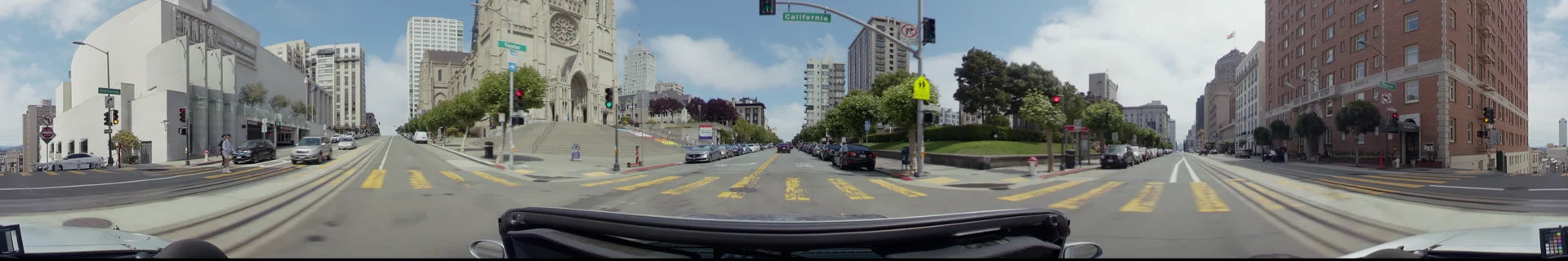 A wide city street in San Francisco featuring parked cars, tall residential buildings, and a wide pedestrian staircase under a partly cloudy sky.