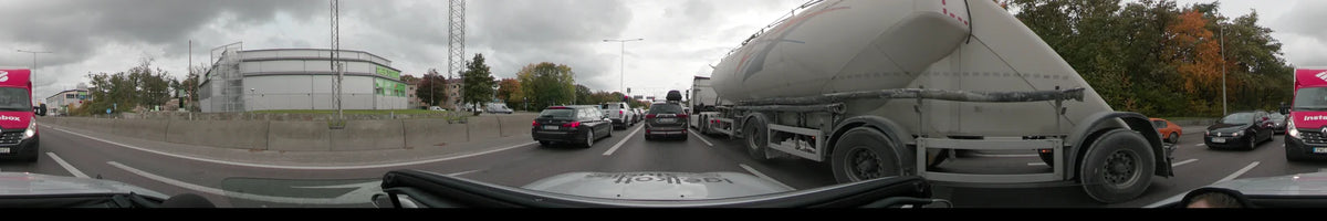 A large silver tanker truck and other vehicles share the road in Stockholm, Sweden, on an overcast autumn day. The perspective is from a car.