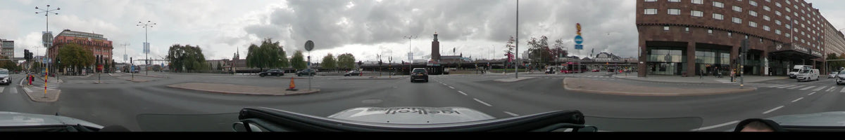 Under an overcast autumn sky, a car navigates a city intersection toward the Stockholm Central Station tower in Stockholm, Sweden, during the day.