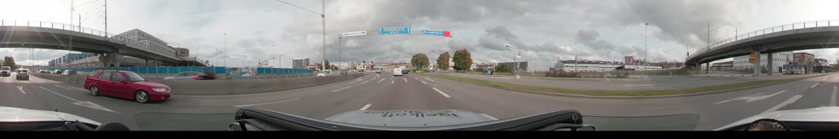 A car travels toward overhead signs for Kista and Sundbyberg on a highway in Stockholm, Sweden, while the autumn day is overcast.