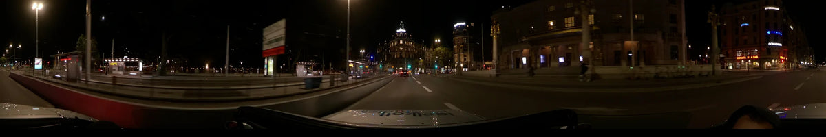 Brightly lit buildings, including the Grand Hôtel, flank a city road in Stockholm, Sweden, as a car passes on a clear autumn night.
