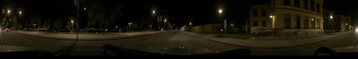 Streetlights illuminate a road and a long building in Stockholm, Sweden, as a car drives by on a clear autumn night.