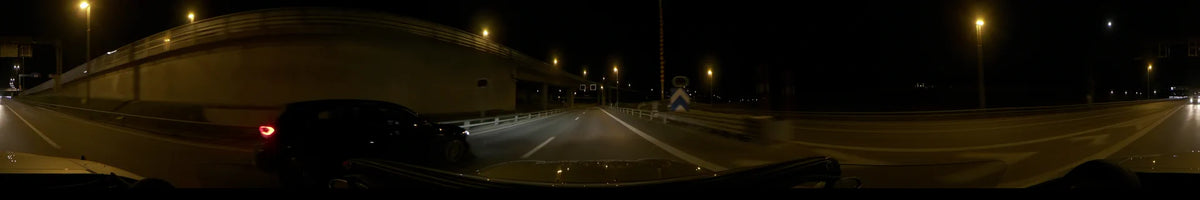 Passing under an overpass, a car drives along a road in Stockholm, Sweden, beneath glowing streetlights on a clear autumn night.