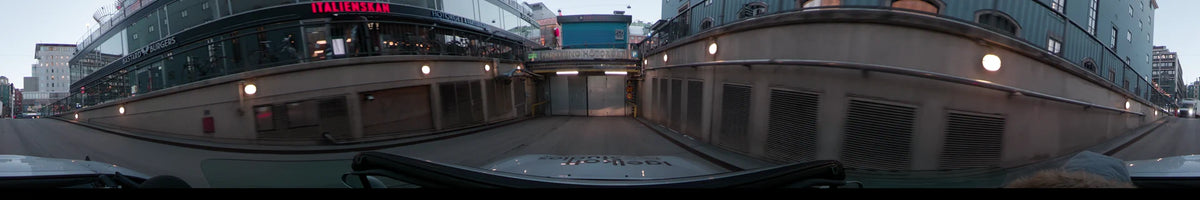 In Stockholm, Sweden, a car approaches the Parkering Hötorget entrance during a clear winter dawn, flanked by concrete walls with metal ventilation grilles.