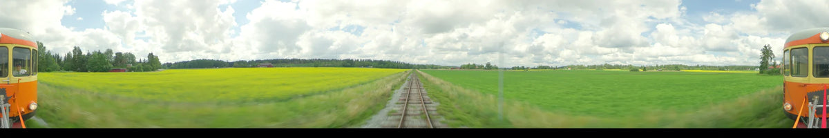 View from a train moving through rural Uppsala, Sweden, during a summer day. The scene shows yellow and green fields under a partly cloudy sky.