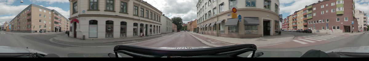 A street in Uppsala lined with multi-story buildings and a dedicated bike lane under a partly cloudy sky.