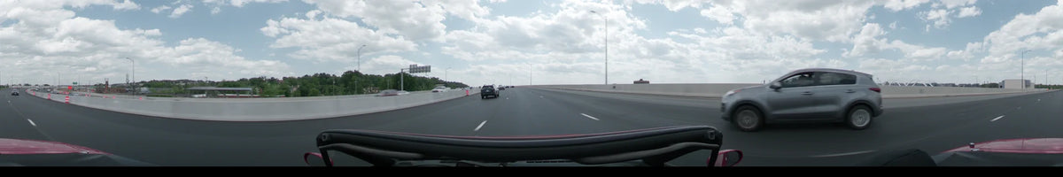 Roadside greenery and other vehicles accompany a car traveling on a multi-lane highway in Washington during a partly cloudy spring afternoon.