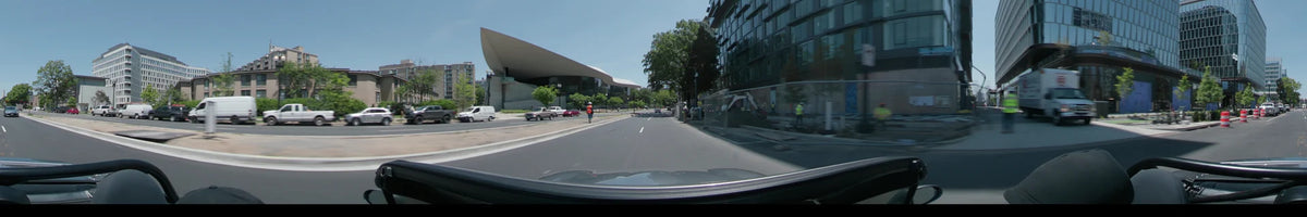 Beside the National Gallery of Art East Building, a car drives through Washington, United States, on a clear spring day past road workers and parked cars.