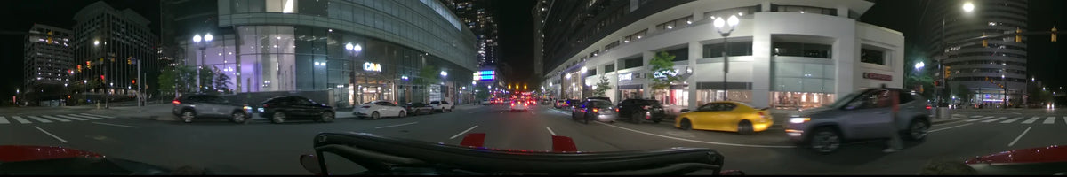 A car drives along a city street in Washington, United States, on a clear spring night, passing tall buildings and other vehicles under bright street lights.