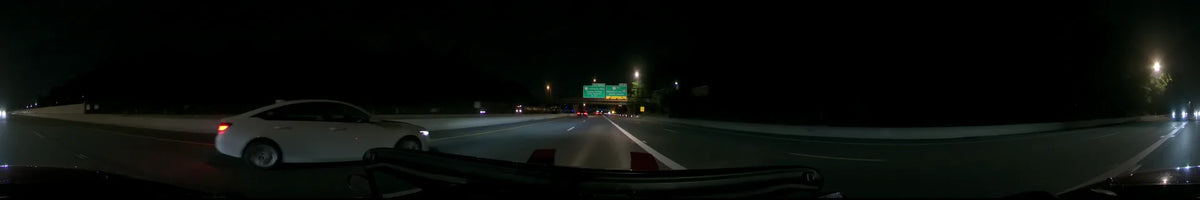 Overhead signs for Dulles Airport and Leesburg Pike guide a car traveling along a highway in Washington, United States, on a clear spring night.