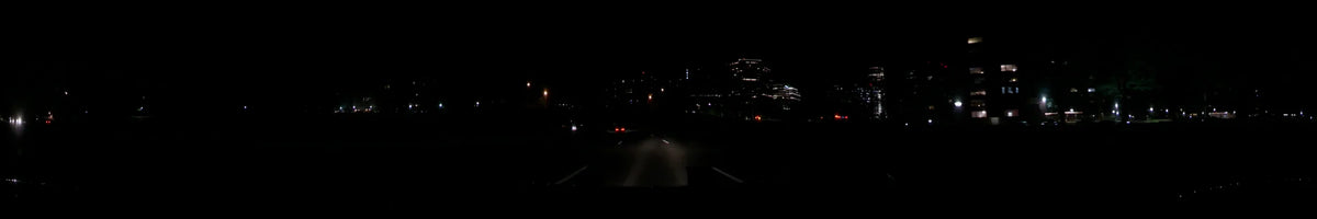 Illuminated city buildings and distant red taillights are visible from a car traveling through Washington, United States, on a clear spring night.