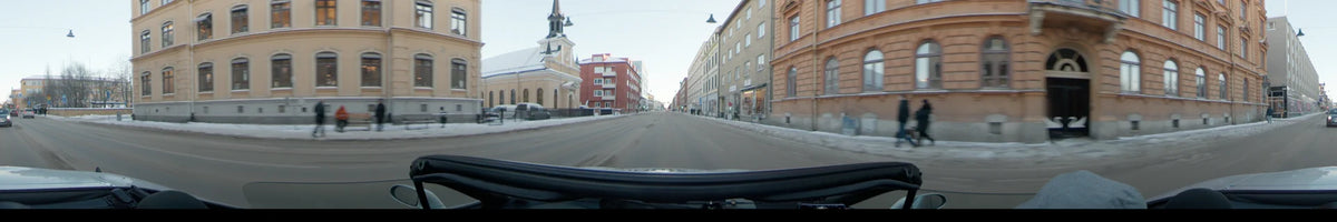 In Uppsala, Sweden, a car travels along a snowy city street on a clear winter day, flanked by a red building and a cream-colored church.